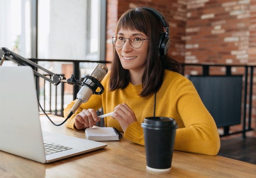 Female podcaster recording podcast at her desk Female podcaster recording podcast at her desk